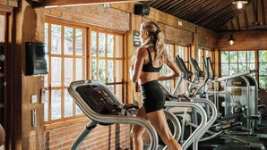 A gym with treadmills, a brick wall, and wooden beams.