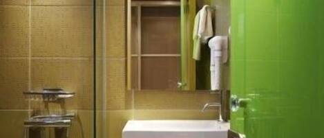 A modern bathroom with a glass shower enclosure, a white sink, and a green door.