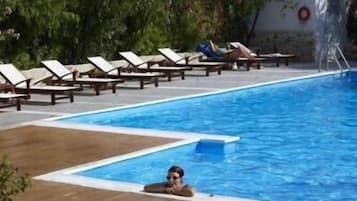 Una piscina al aire libre, sombrillas, sillones reclinables de piscina