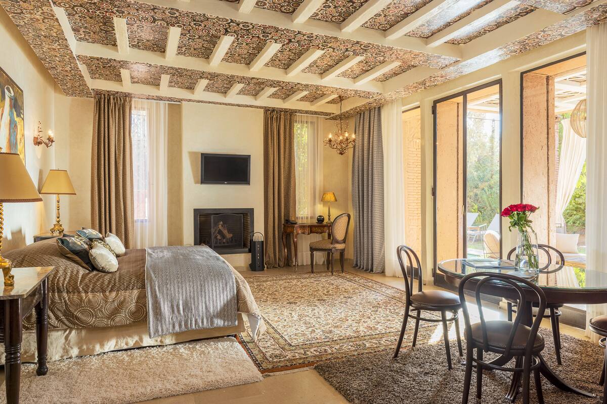 Une chambre avec un grand lit, un bureau et une chaise, une télévision et une vue sur l’extérieur.