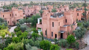 Un conjunto de edificios tradicionales con techos de tejas rojas y abundante vegetación al frente.