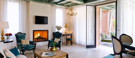 A spacious living room with a fireplace, comfortable seating, and a view through an open door.