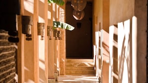 Un pasillo con vigas de madera, lámparas colgantes y columnas decoradas.