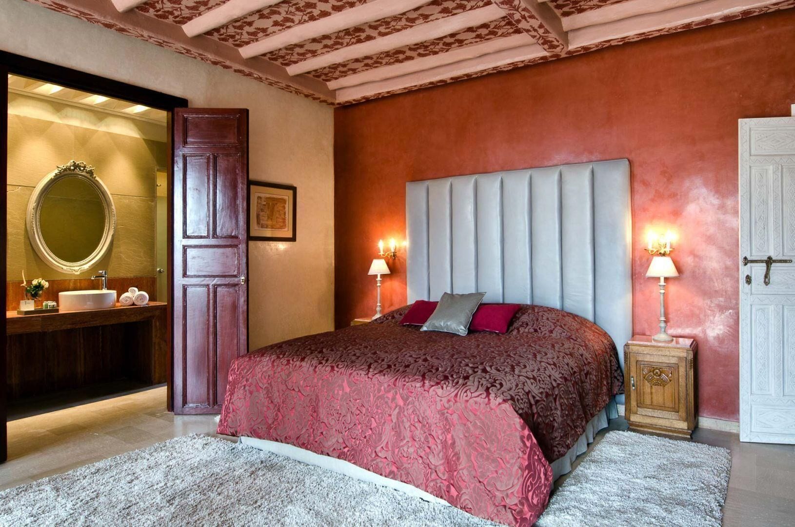 A bedroom with a large bed, a vanity with a mirror, and two bedside lamps.