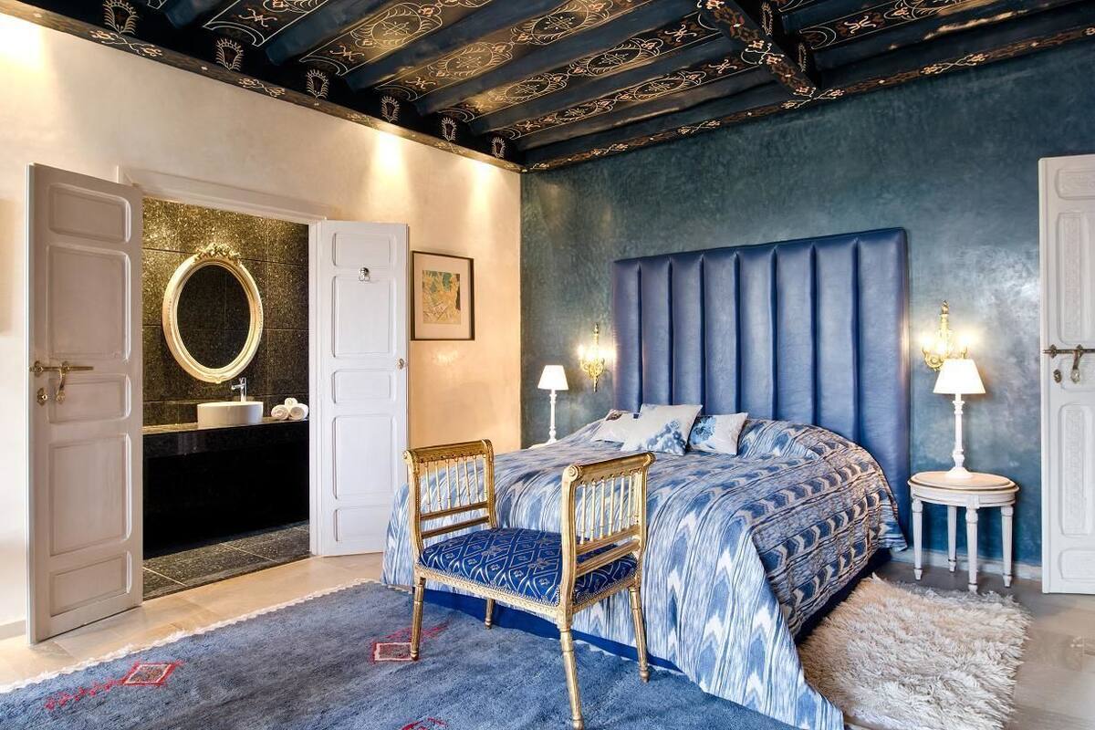 Une chambre avec un grand lit, une coiffeuse avec un miroir et une chaise.