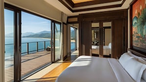 Ein Hotelzimmer mit einem großen Bett, Meerblick und einem Balkon.