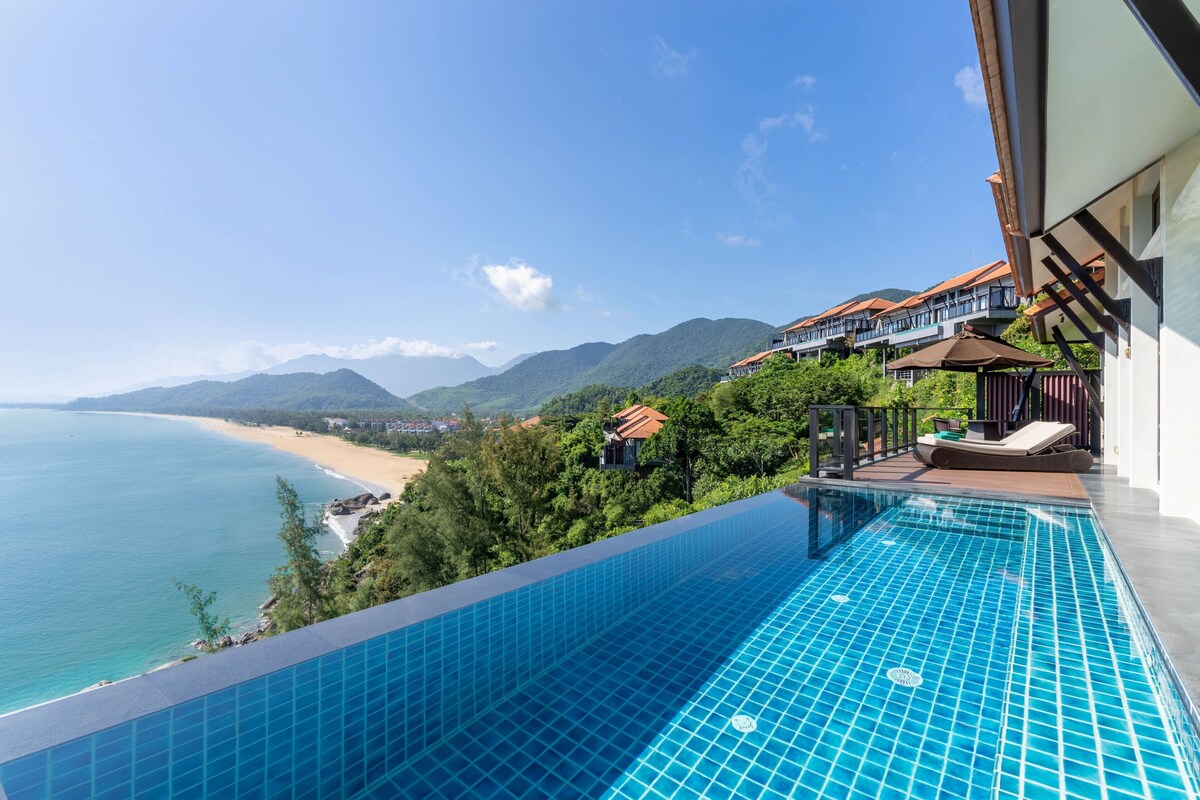 A swimming pool with a view of the beach and mountains.