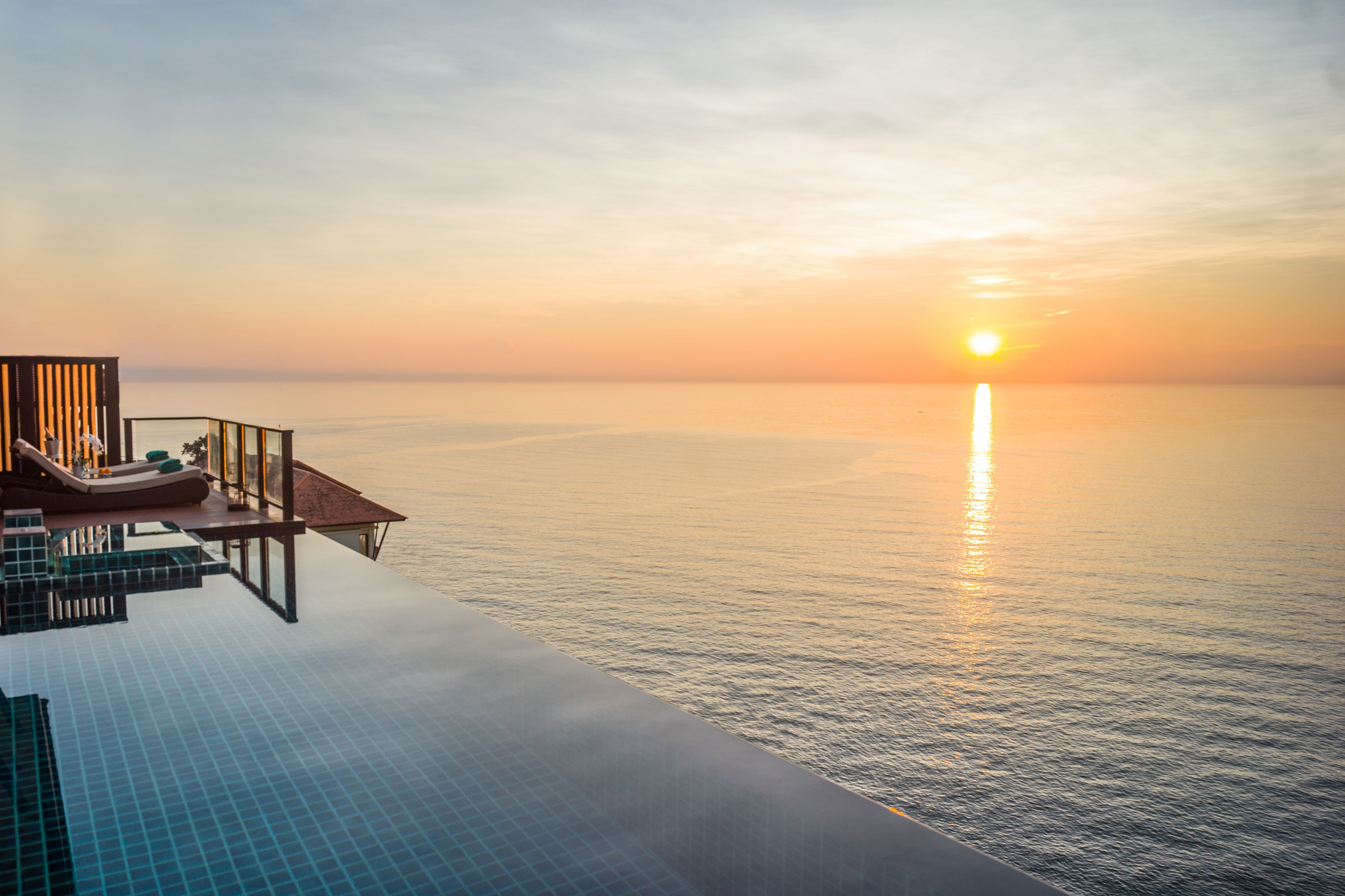 A luxurious infinity pool with a clear view of the ocean and a sunset.