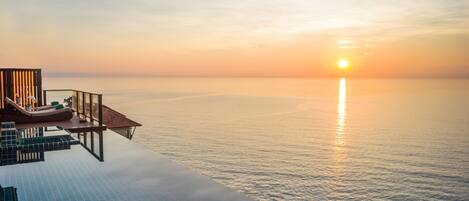 A luxurious infinity pool with a clear view of the ocean and a sunset.