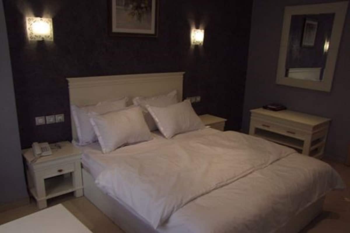 A bedroom with a bed, nightstands, a bedside table, and a mirror.