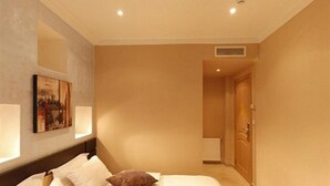 A hotel room with a bed, pillows, a painting on the wall, and a door leading to another room. - Dar El Ikram (Algiers)