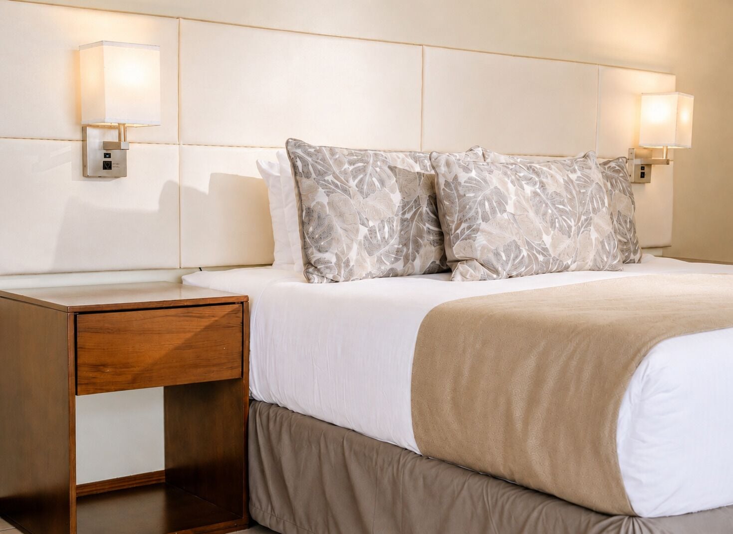 Une chambre d’hôtel avec un lit, des tables de chevet et des lampes fixées au mur.