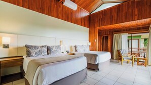A hotel room with two beds, wooden ceiling, tiled floor, and a balcony with a view.