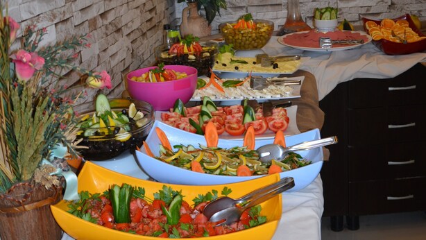 A buffet table with various food items and a potted plant. - Kleopatra Bebek Hotel (Alanya)