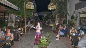 An outdoor dining area with tables and chairs, surrounded by buildings and outdoor seating. - Kleopatra Bebek Hotel (Alanya)
