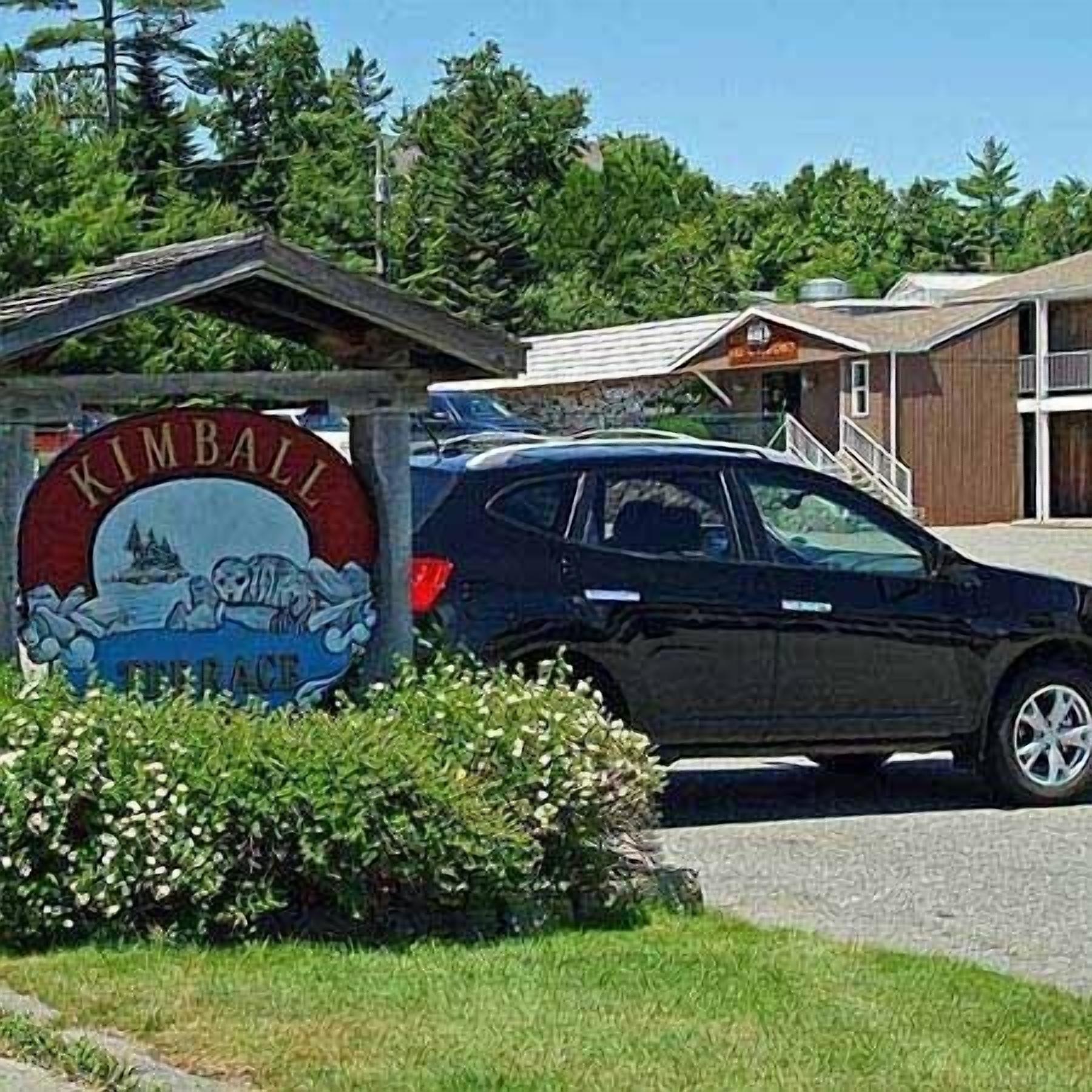 A sign for Kimball Beach with a car parked in front.