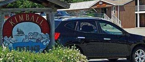 A sign for Kimball Beach with a car parked in front.
