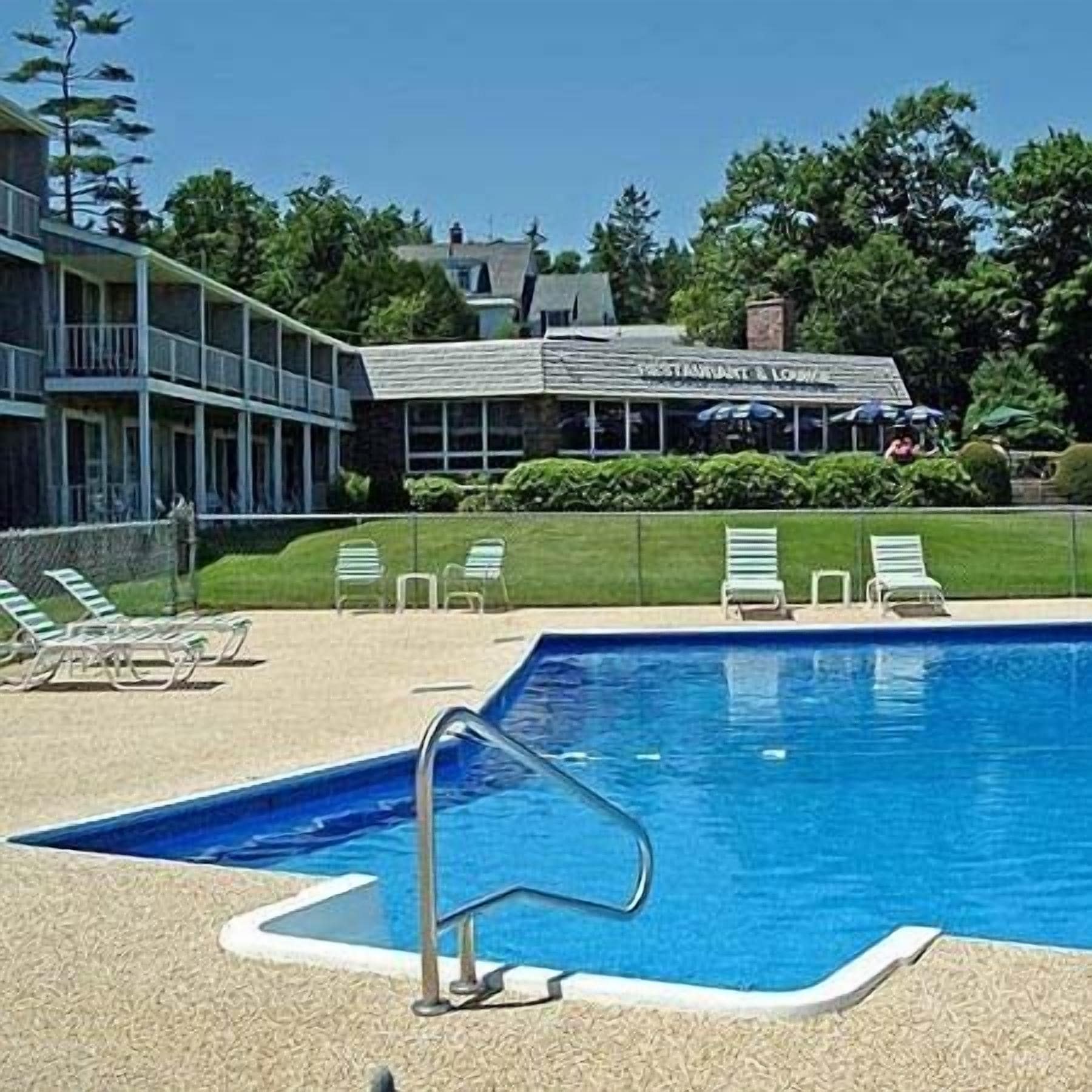 A swimming pool with lounge chairs and a restaurant in the background.
