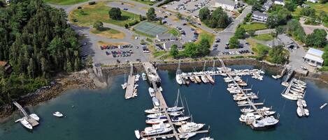An aerial view of a marina with numerous boats docked, surrounded by residential buildings and a large parking area.
