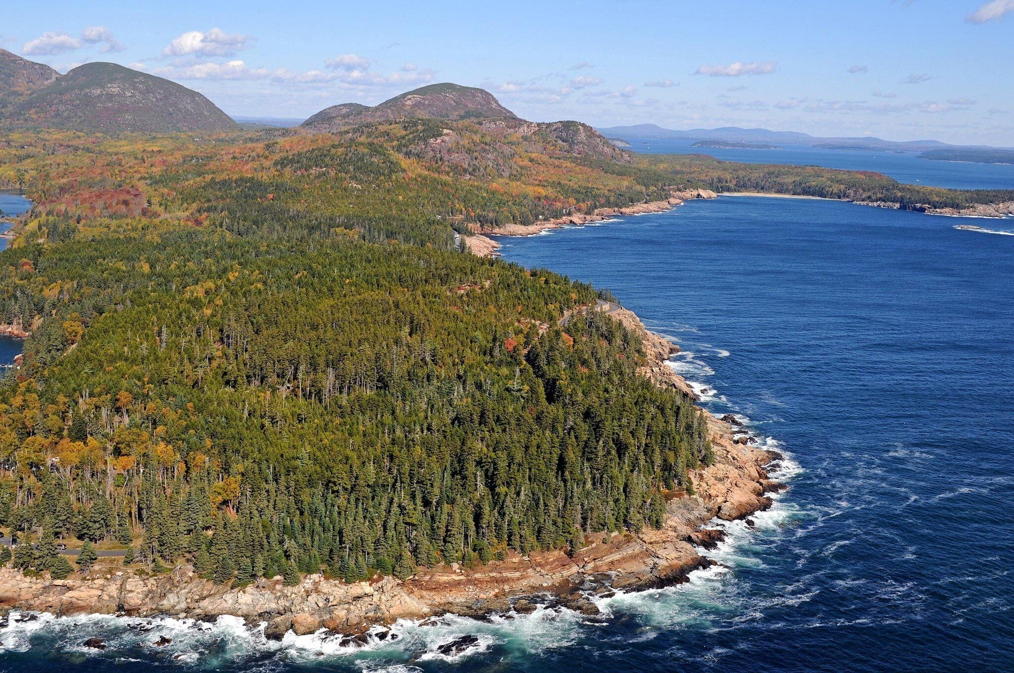 Un paysage côtier caractérisé par de vastes forêts, une côte rocheuse et des montagnes lointaines.