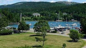 A coastal road with a marina, boats, and a building in the background. - Kimball Terrace Inn Northeast Harbor (Northeast Harbor)
