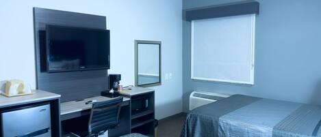 Hotelkamer met een bureau, een televisie, een spiegel, een raam met zonwering en twee bedden.