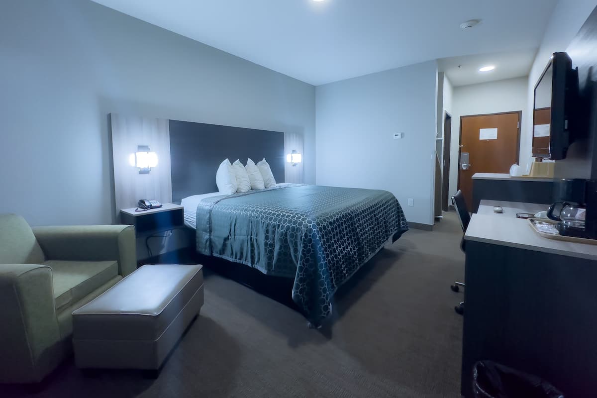 A hotel room with a bed, a desk, a chair, and a small table.
