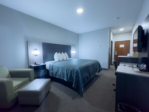 Une chambre d’hôtel avec un lit, un bureau, une chaise et une petite table.