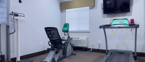 A fitness center with a treadmill, stationary bike, and weight machine.