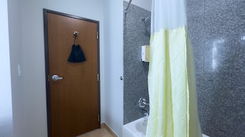 Ein Badezimmer mit Duschvorhang, Tür und Fliesenboden.