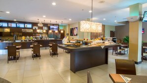 A modern hotel lobby with a central bar area, seating arrangements, and a digital menu display. - Courtyard by Marriott San Jose Airport Alajuela (Rio Segundo)