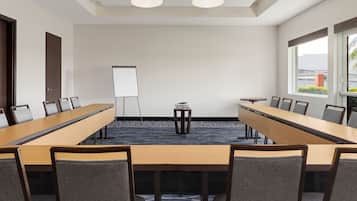 A conference room with a long table, chairs, a whiteboard, and a small table with a lamp.