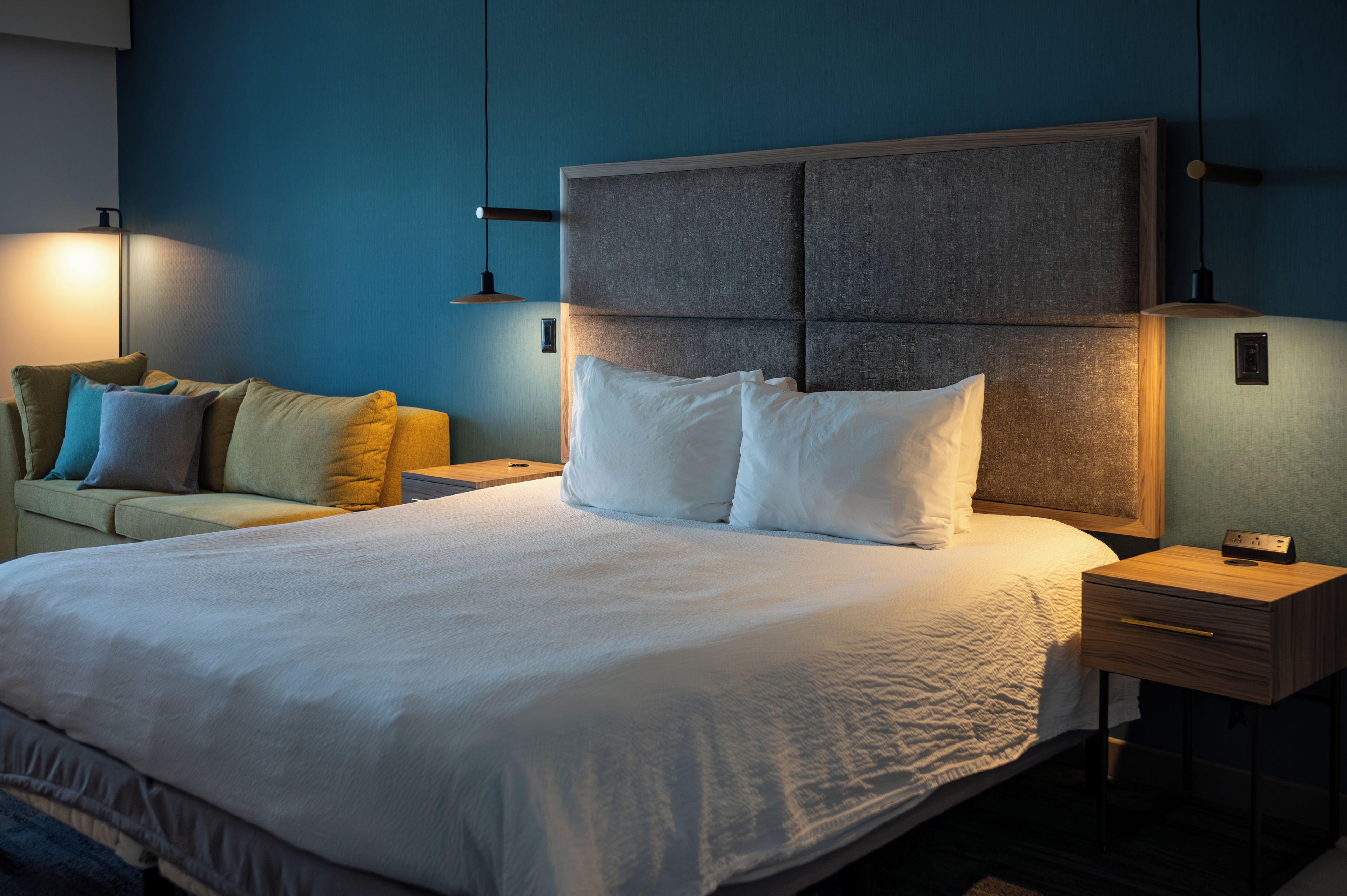 Une chambre d’hôtel avec un grand lit, un canapé et une table de chevet avec une lampe.