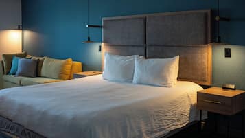 Une chambre d’hôtel avec un grand lit, un canapé et une table de chevet avec une lampe.