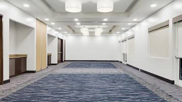 A hotel corridor with a patterned carpet, recessed lighting, and doors on both sides.