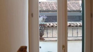 Una habitación con puerta de vidrio corredera que da a un balcón con una planta en maceta y techo de tejas.