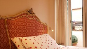 Una cama con un cabecero estampado de motivos rojos y ropa de cama blanca con diseños florales rojos.