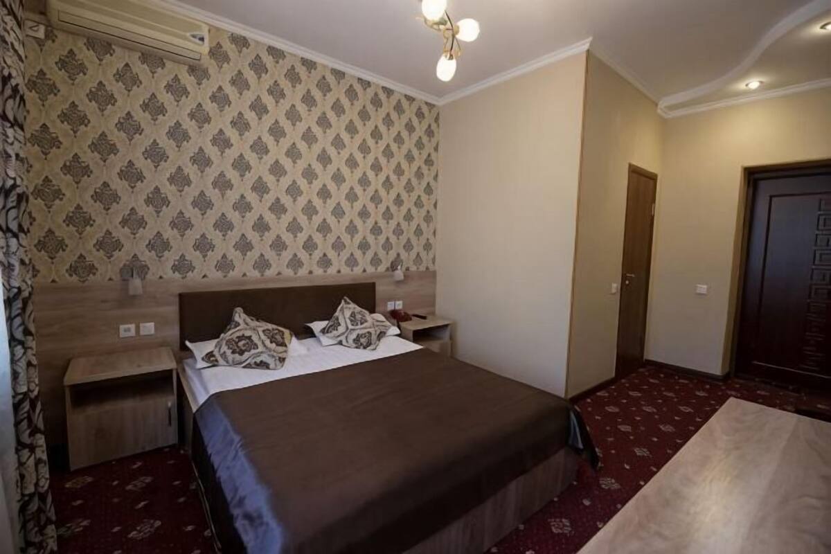 A hotel room with a bed, nightstands, a wardrobe, and a door.
