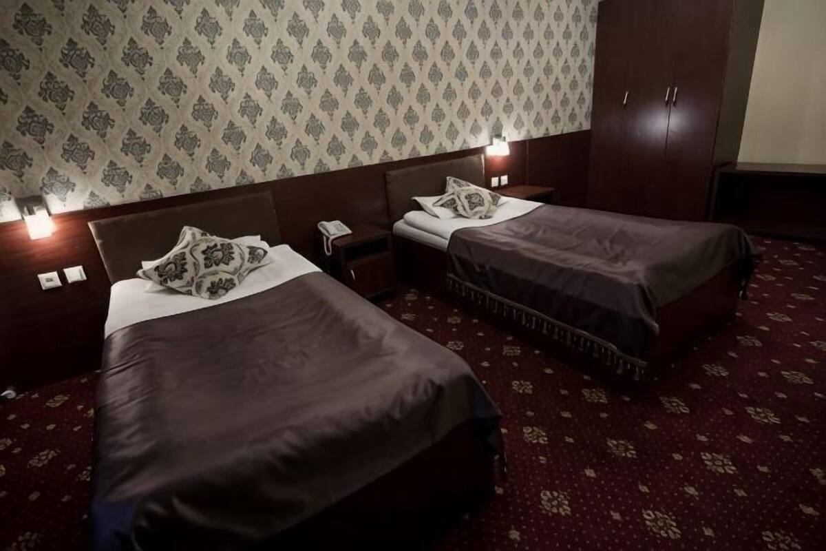 A hotel room with two beds, a nightstand, a telephone, and a wardrobe.