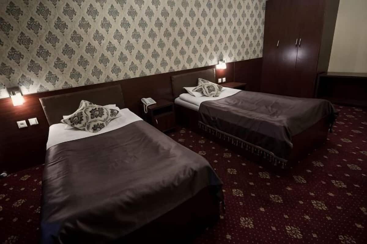 A hotel room with two beds, a nightstand, a telephone, and a wardrobe.