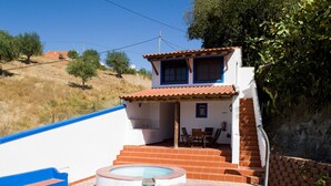 Una casa con piscina, un patio con mobiliario exterior y una escalera que sube al piso superior.
