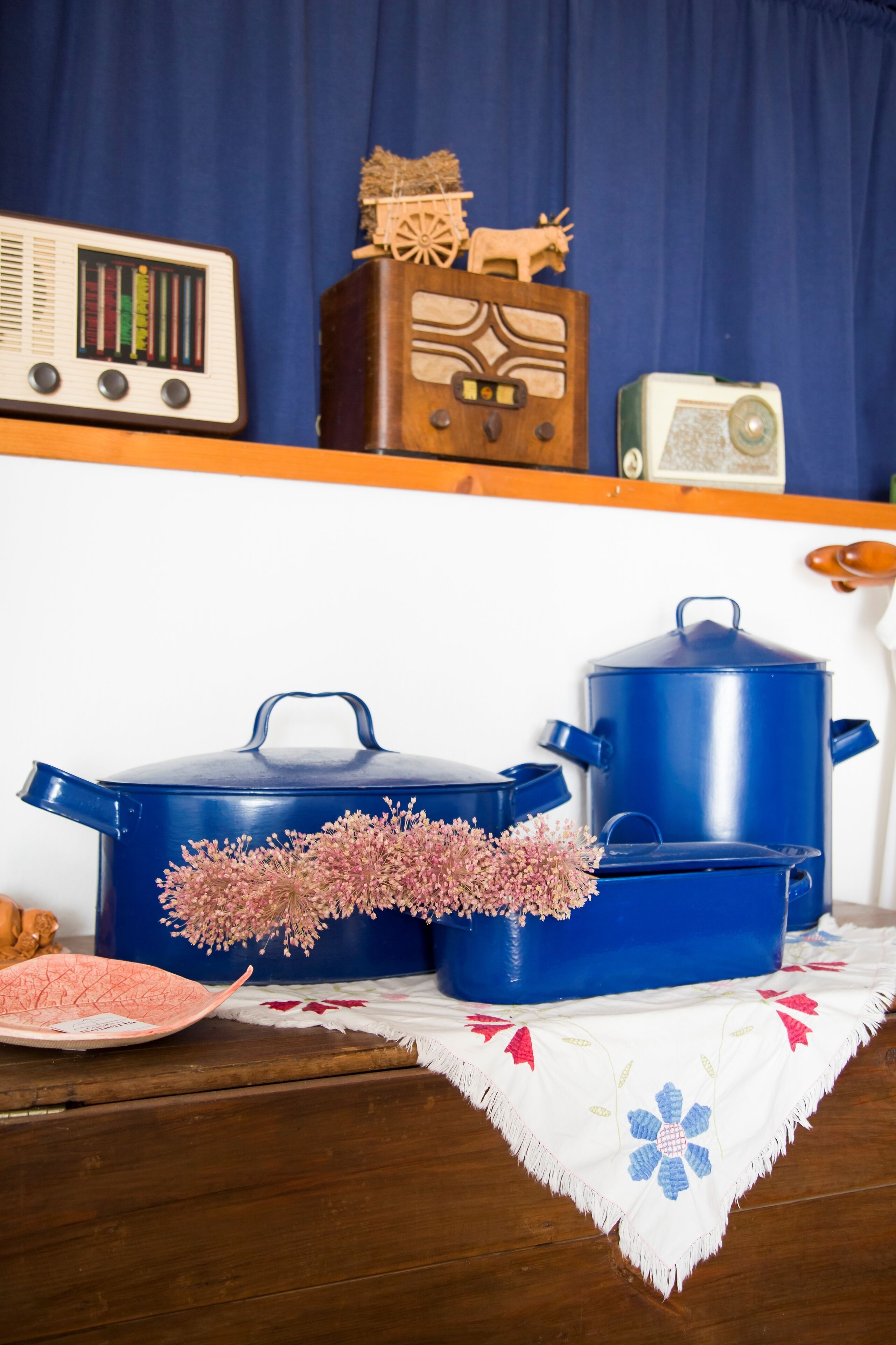 Een keukenhoek met blauwe kookpannen, een radio en decoratieve objecten op een plank.