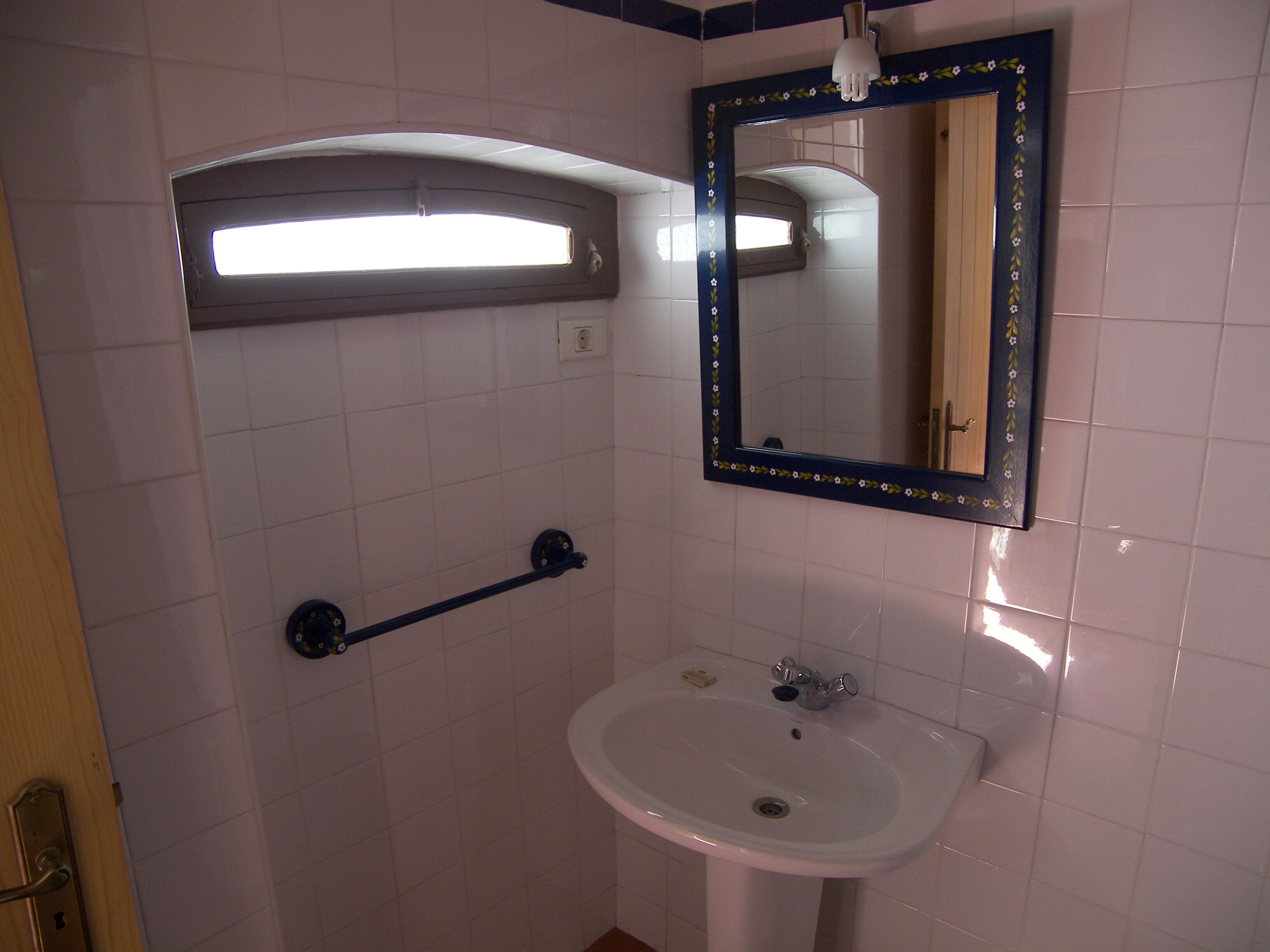 A bathroom with a white sink, a mirror with a floral frame, and a towel rack.