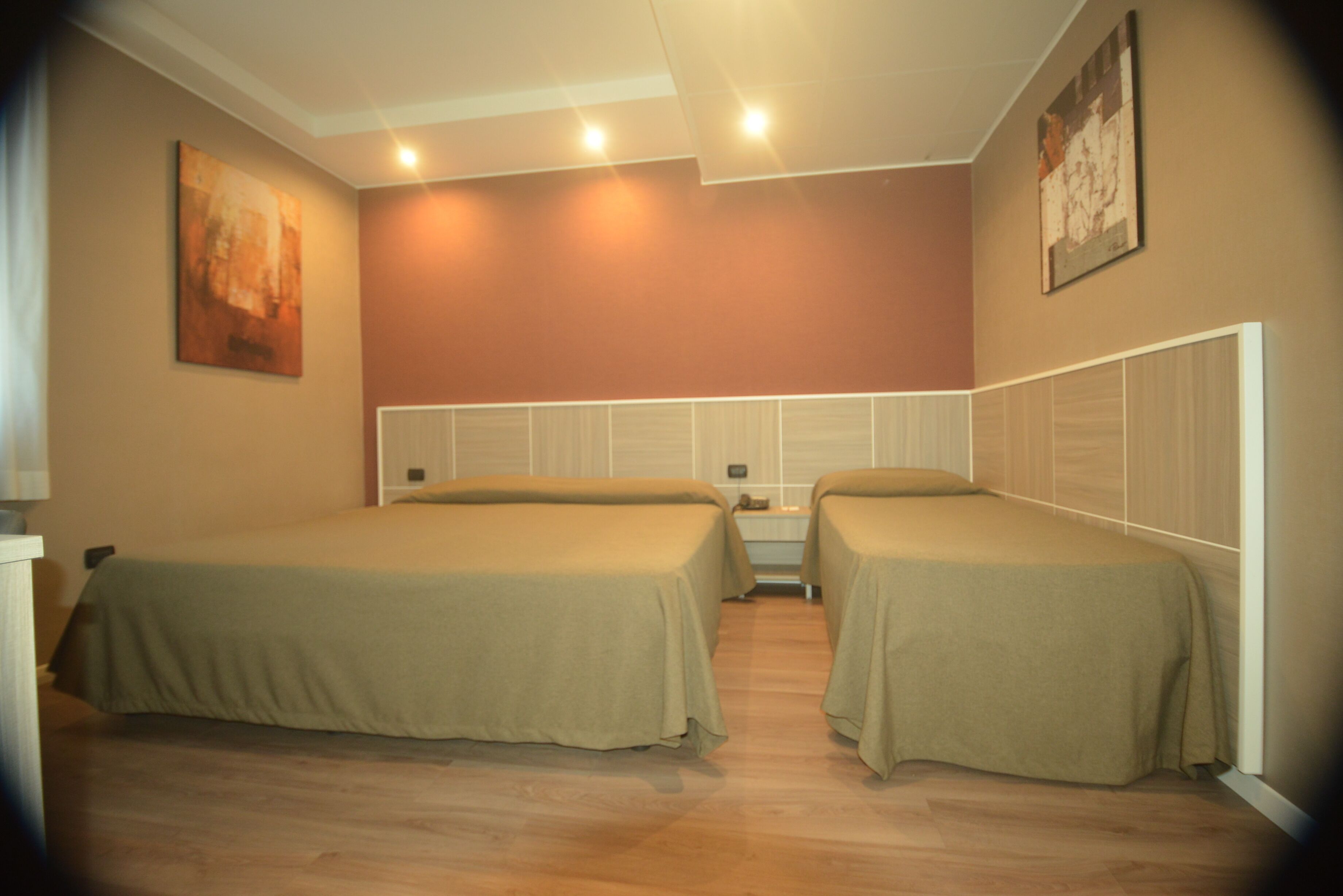 Una habitación con dos camas individuales, una mesita de noche y una estantería en la pared.