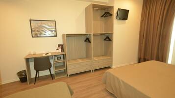 Une chambre d’hôtel équipée d’un lit, d’un bureau, d’une chaise, d’une armoire et d’un téléviseur.