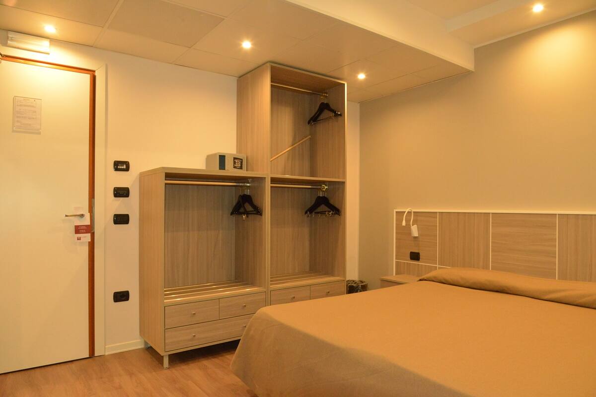 A bedroom with a bed, a wardrobe, and a bedside table.