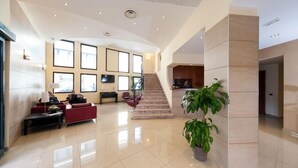 Un vestíbulo espacioso con una escalera curva, un mostrador de recepción y una zona de estar.