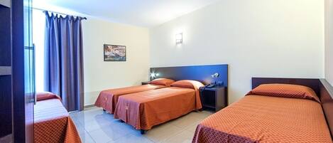 A hotel room with three beds, a ceiling fan, a nightstand, and a window with curtains.