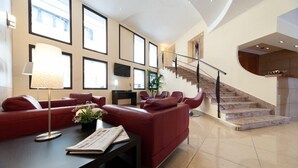 Amplia sala de estar con un sofá rojo, una mesa de centro con lámpara y una escalera que lleva a un nivel superior.
