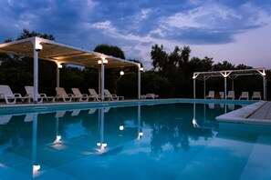 Una piscina al aire libre de temporada, sombrillas, tumbonas